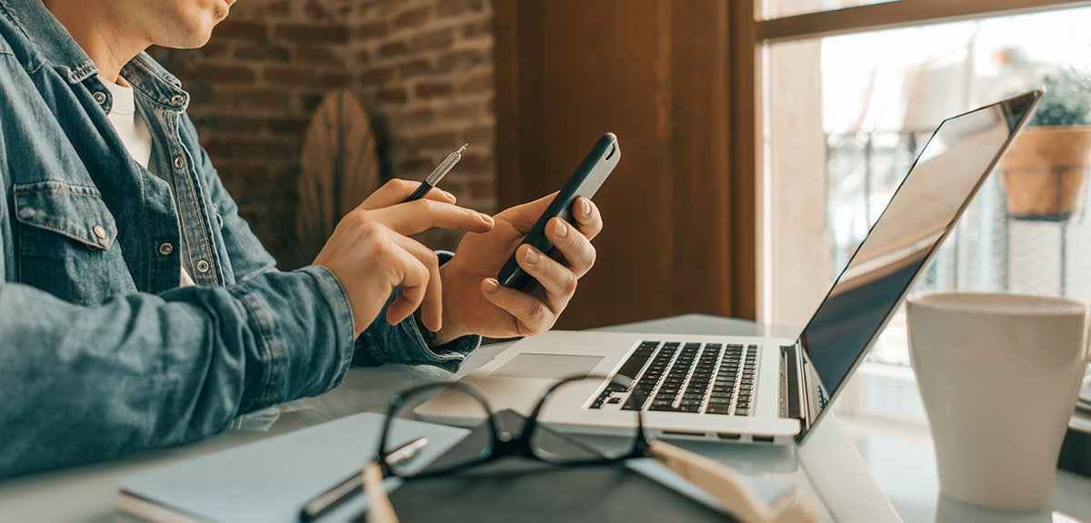 remote working on a mobile and laptop 2 man-remote-working-with-phone